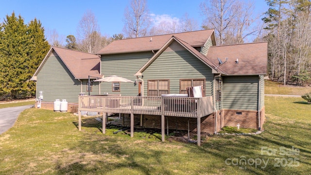 rear view of property featuring a wooden deck and a lawn