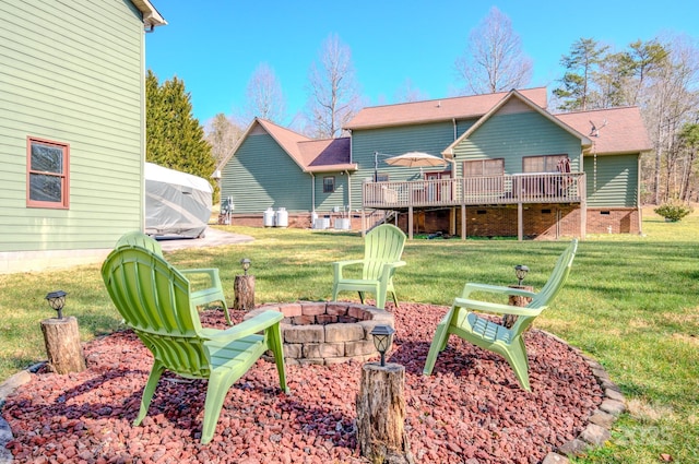 back of house featuring a wooden deck, a lawn, and an outdoor fire pit