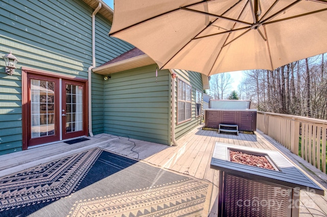 deck with a hot tub, french doors, and an outdoor fire pit