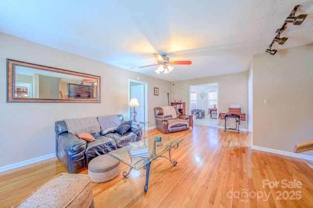 living room with ceiling fan, rail lighting, hardwood / wood-style floors, and a textured ceiling