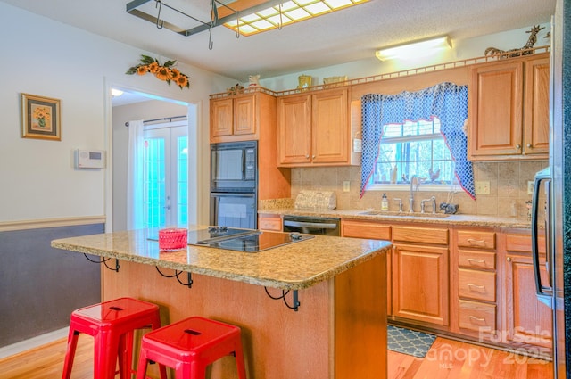 kitchen featuring a center island, a breakfast bar, sink, and black appliances