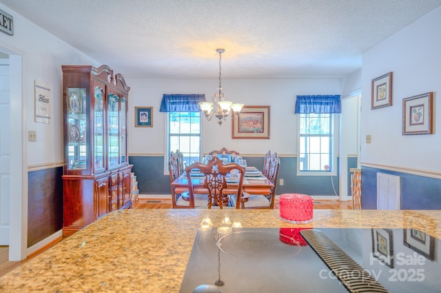 dining room with a notable chandelier, hardwood / wood-style floors, and a textured ceiling