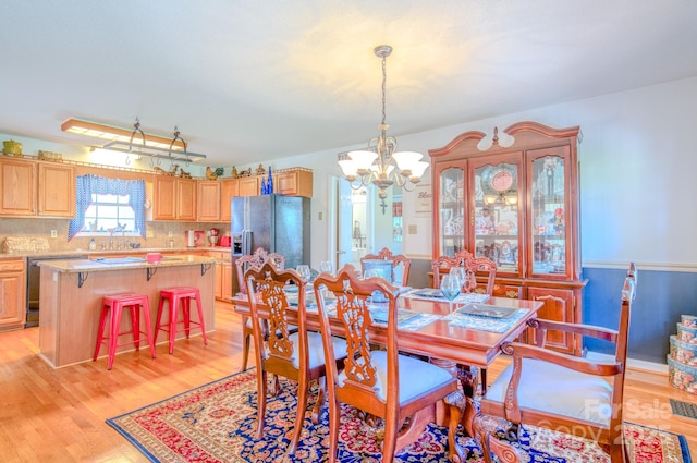 dining area featuring sink, an inviting chandelier, and light hardwood / wood-style floors