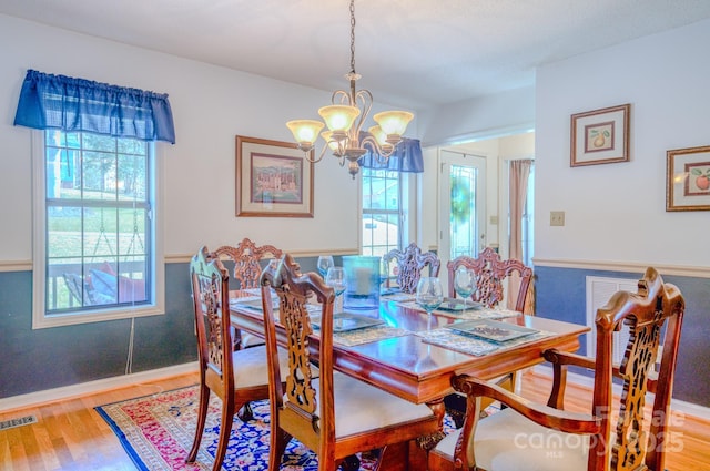 dining space featuring light hardwood / wood-style floors and a notable chandelier