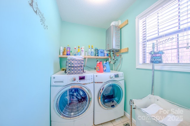 laundry area featuring light tile patterned flooring, tankless water heater, washer and dryer, and a textured ceiling