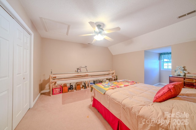 carpeted bedroom featuring lofted ceiling, a textured ceiling, a closet, and ceiling fan