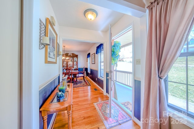 hall with hardwood / wood-style flooring, an inviting chandelier, and french doors