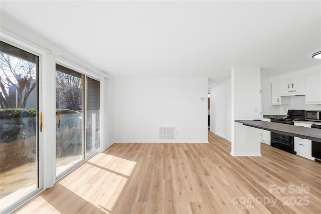 kitchen with black range, light hardwood / wood-style flooring, and white cabinets