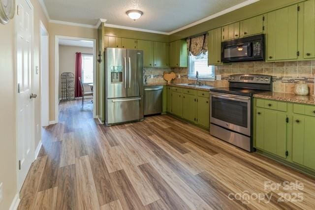 6108 Gold Creek Estate Dr, Hickory, NC 28601 - kitchen with stainless steel appliances, green cabinets, backsplash, light wood-style floors, and crown molding