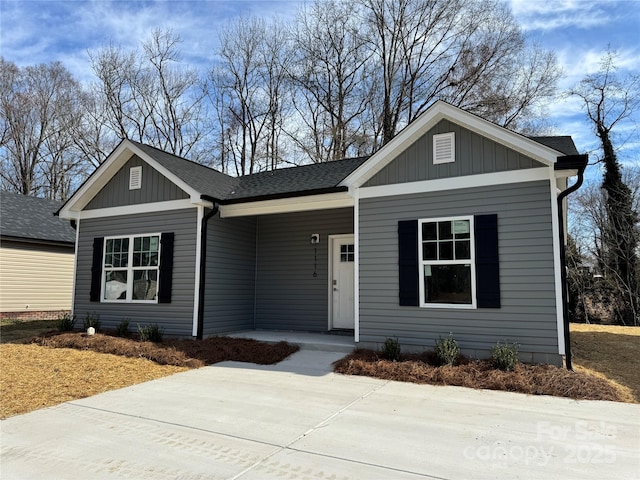 ranch-style home featuring board and batten siding, covered porch, and a shingled roof