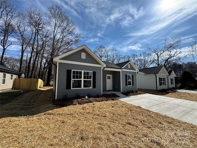 view of front of house featuring a front yard, fence, board and batten siding, and driveway