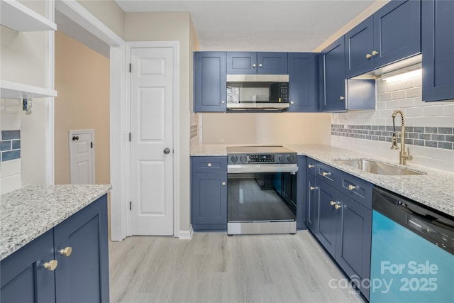 kitchen featuring light stone counters, sink, stainless steel appliances, and blue cabinets