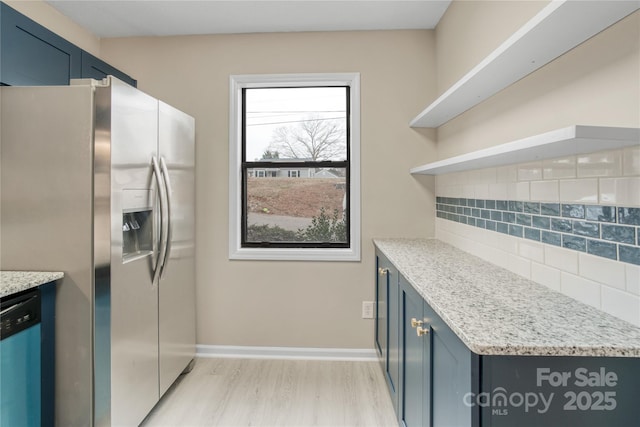 kitchen featuring appliances with stainless steel finishes, tasteful backsplash, light stone counters, blue cabinetry, and light wood-type flooring