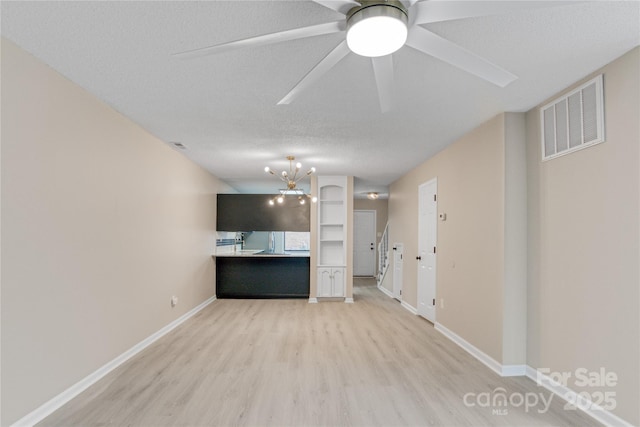 unfurnished living room with an inviting chandelier, light hardwood / wood-style flooring, and a textured ceiling