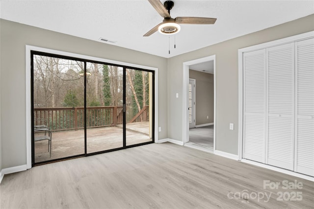 unfurnished bedroom featuring ceiling fan, a closet, light hardwood / wood-style flooring, and access to outside