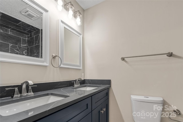 bathroom with vanity, a textured ceiling, and toilet