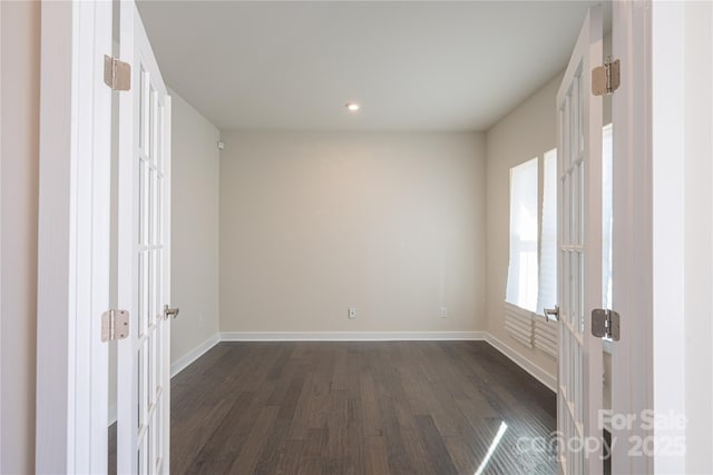 unfurnished room with dark wood finished floors and baseboards