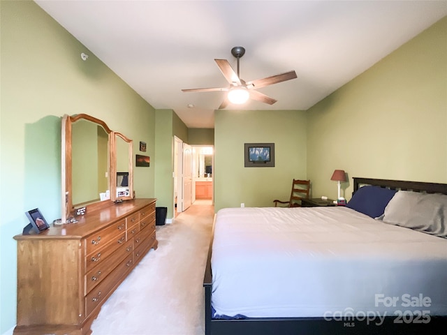 bedroom with ceiling fan, ensuite bath, and light carpet