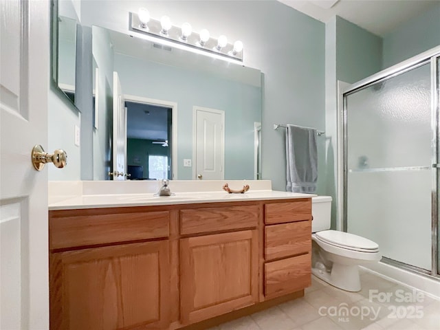 bathroom featuring vanity, toilet, tile patterned floors, and a shower with shower door