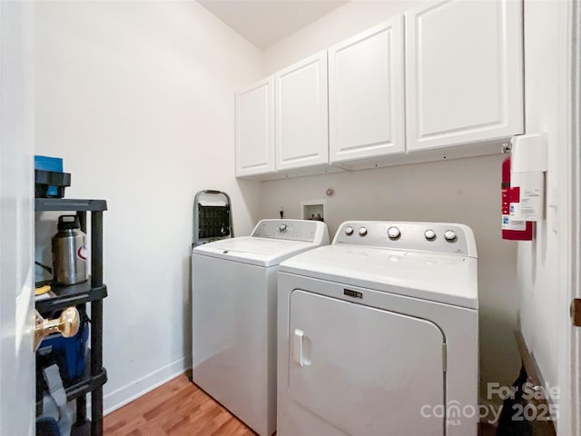 washroom featuring cabinets, washer and dryer, and light hardwood / wood-style flooring