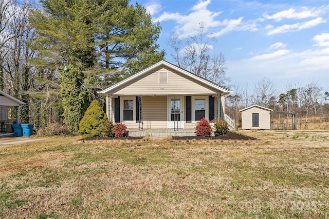 view of front of house featuring a porch, a front yard, and a storage shed