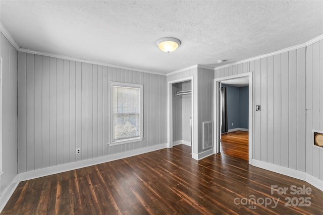 unfurnished bedroom featuring dark hardwood / wood-style flooring, crown molding, a closet, and a textured ceiling