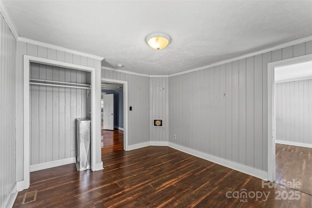 unfurnished bedroom featuring crown molding, dark hardwood / wood-style floors, and a closet