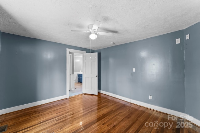 empty room with ceiling fan, hardwood / wood-style floors, and a textured ceiling