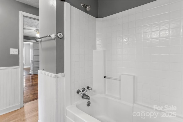 bathroom featuring hardwood / wood-style flooring, shower / tub combination, and a textured ceiling