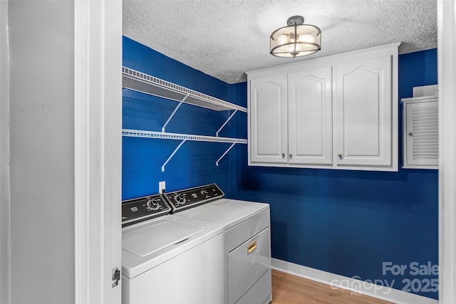 laundry area featuring separate washer and dryer, light hardwood / wood-style flooring, cabinets, and a textured ceiling