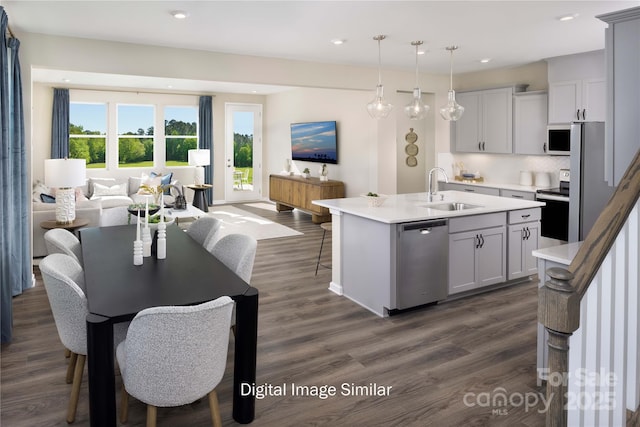 kitchen featuring sink, dark wood-type flooring, appliances with stainless steel finishes, an island with sink, and decorative light fixtures