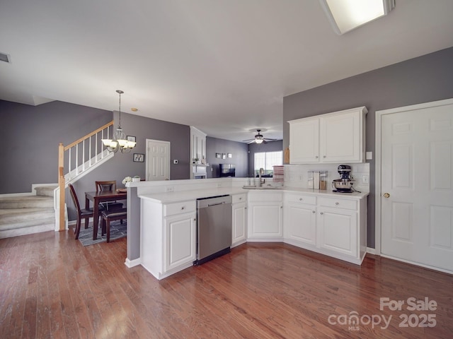 kitchen featuring decorative light fixtures, white cabinets, hardwood / wood-style flooring, stainless steel dishwasher, and kitchen peninsula