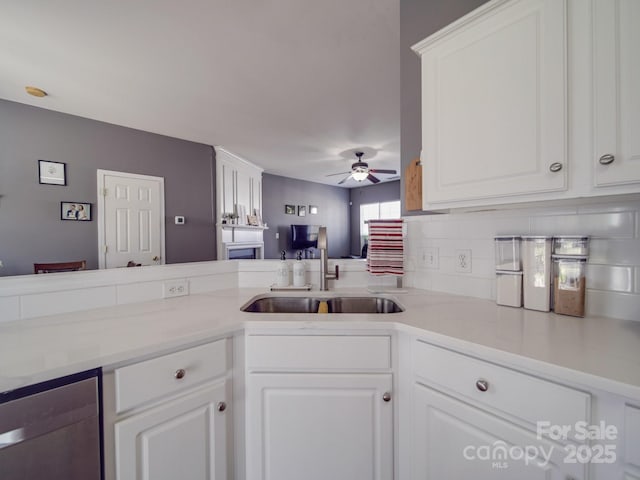 kitchen featuring sink, ceiling fan, backsplash, white cabinets, and stainless steel dishwasher