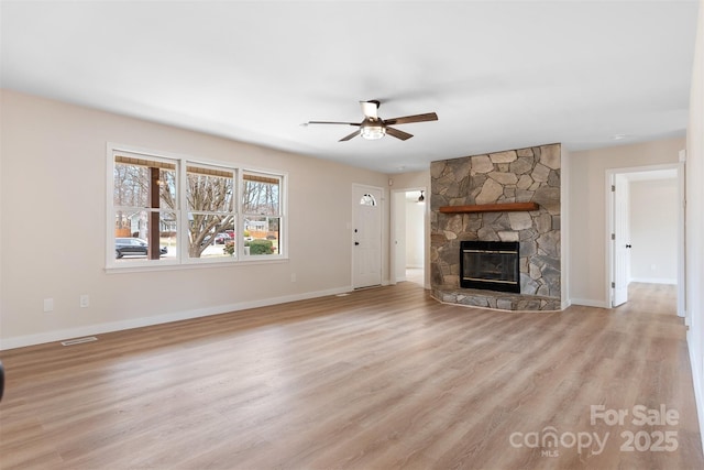 unfurnished living room featuring a stone fireplace, ceiling fan, and light wood-type flooring