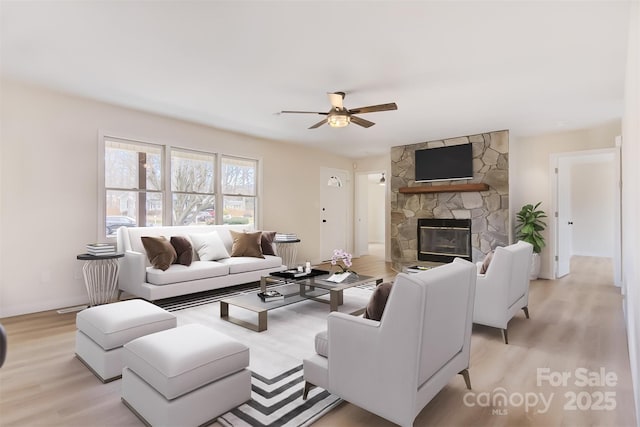 living room featuring ceiling fan, light wood-type flooring, and a fireplace