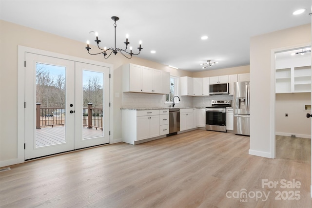 kitchen with stainless steel appliances, sink, white cabinets, and decorative light fixtures