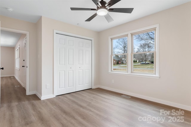 unfurnished bedroom featuring ceiling fan, light hardwood / wood-style floors, and a closet