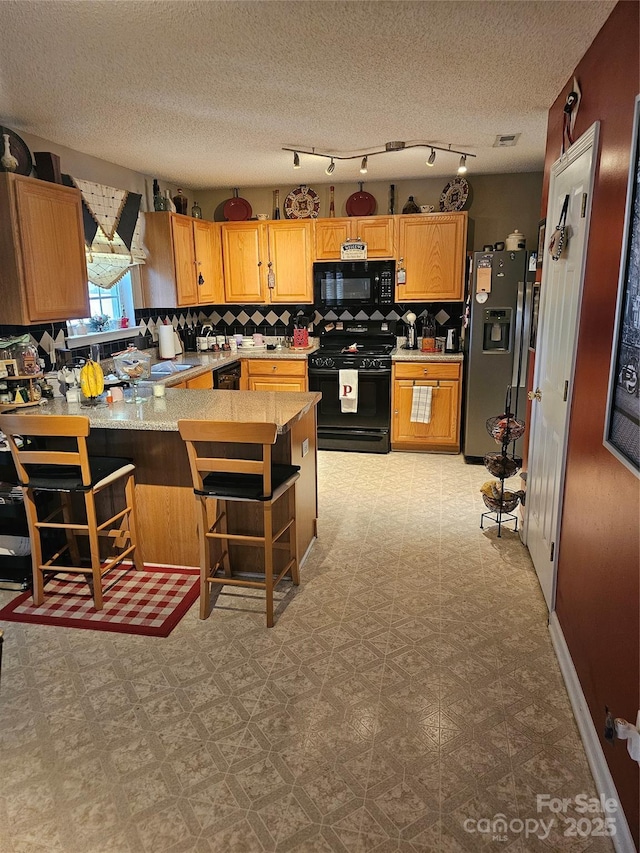 kitchen featuring kitchen peninsula, backsplash, a kitchen breakfast bar, and black appliances