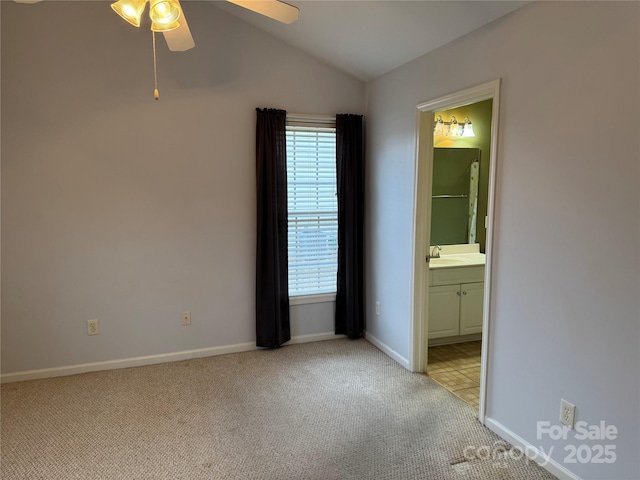 unfurnished bedroom with ensuite bathroom, lofted ceiling, sink, ceiling fan, and light carpet