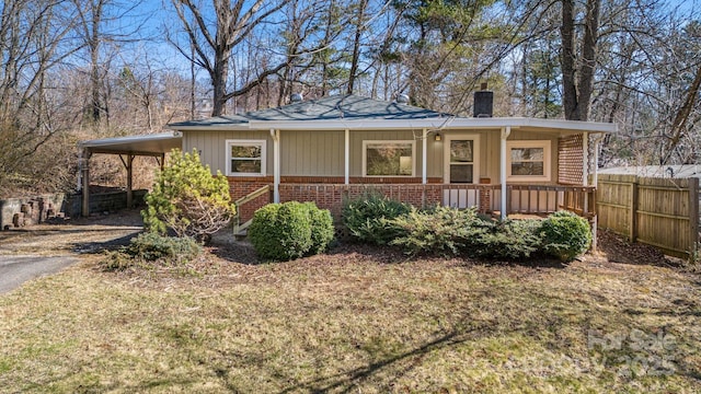 view of front of home featuring a chimney, aphalt driveway, an attached carport, covered porch, and brick siding