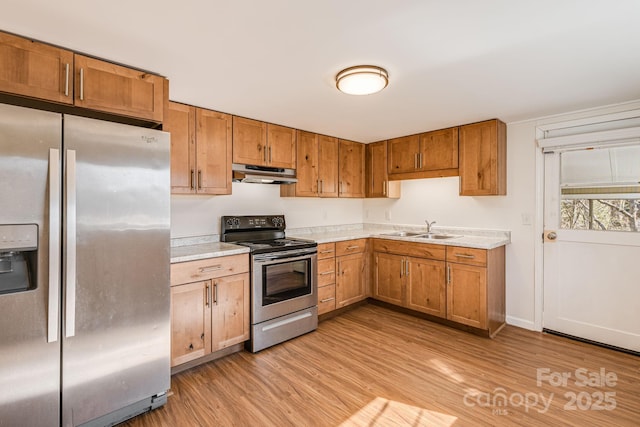 kitchen featuring stainless steel appliances, light countertops, under cabinet range hood, and light wood finished floors