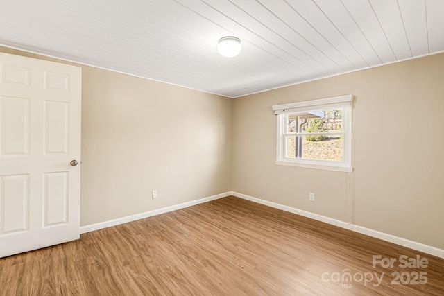 spare room featuring light wood-type flooring, wooden ceiling, and baseboards