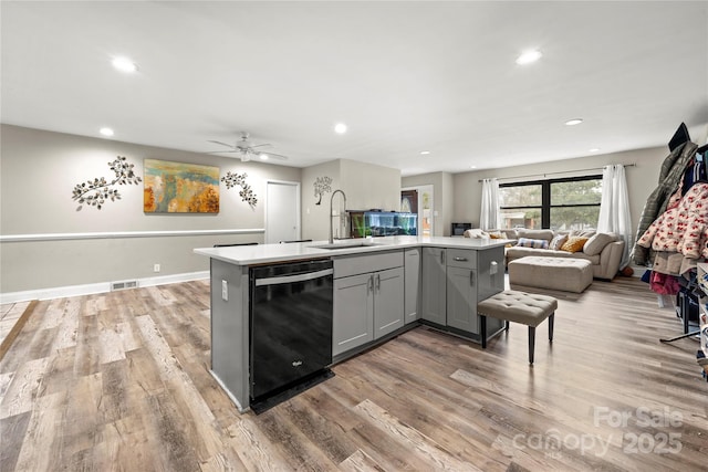 kitchen featuring dishwasher, sink, gray cabinetry, light hardwood / wood-style floors, and a center island with sink