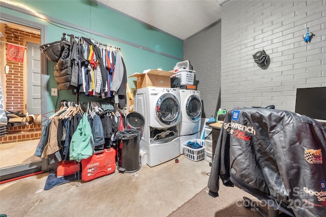 laundry room featuring washing machine and dryer and brick wall