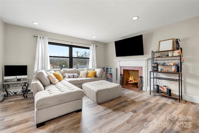 living room featuring a brick fireplace and light hardwood / wood-style floors