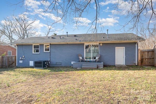 rear view of house featuring central AC unit and a lawn