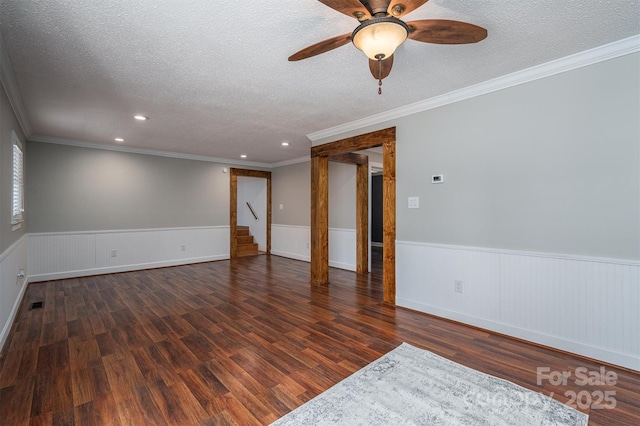 empty room with visible vents, wood finished floors, a textured ceiling, and wainscoting