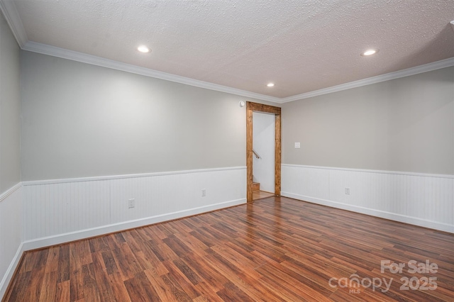 spare room with a wainscoted wall, a textured ceiling, and wood finished floors