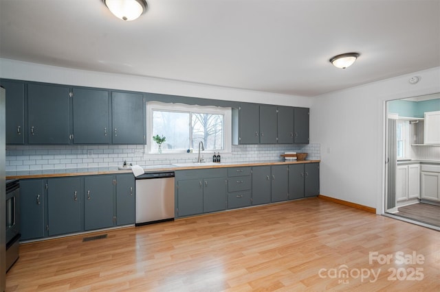 kitchen featuring light wood finished floors, stainless steel dishwasher, backsplash, and a sink