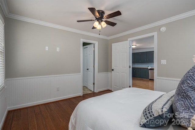 bedroom featuring a ceiling fan, wainscoting, crown molding, and wood finished floors